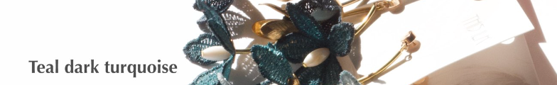 Long collier réglable avec en pendentif trois fleurs de tiaré en dentelle de couleur sarcelle. Au centre de la fleur se trouve une perle nacrée
