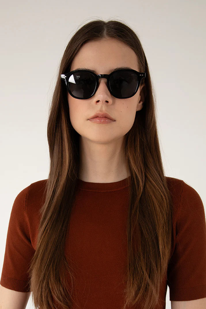 Femme regardant la caméra avec les lunettes Nika noir. Monture ronde polarisée.