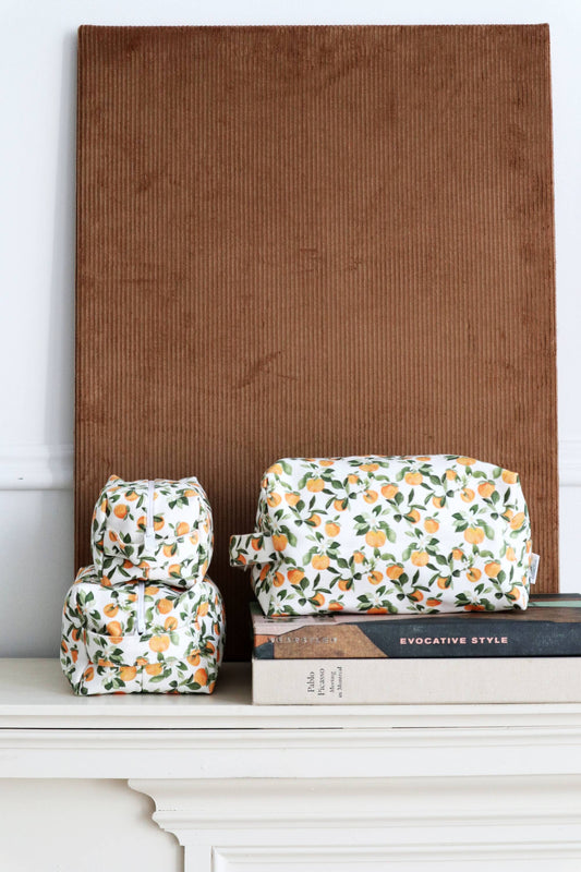 Ensemble de trousses maquillage coton motif clémentine posées sur des livres