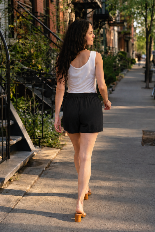 Femme portant le short Anna noir de dos dans une rue de Montréal, avec taille élastique et coupe fluide confortable.