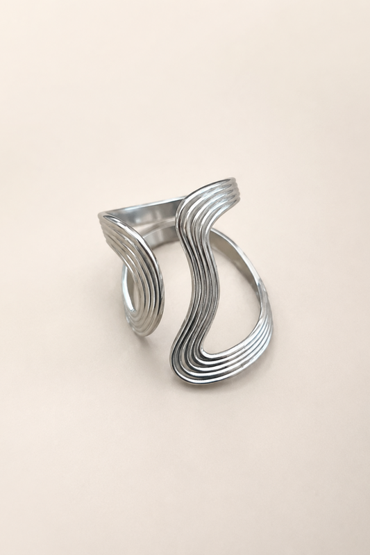 Bague Anna argent présentée seule, avec design ondulé graphique et finition argentée brillante.