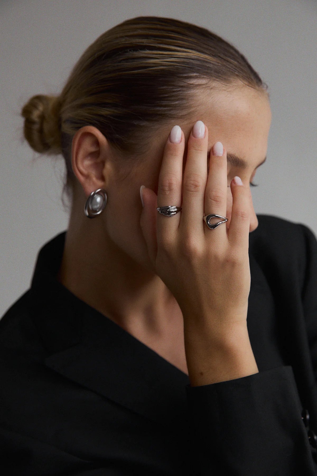 Main portant la bague Gia cachant partiellement le visage – bijou au style épuré