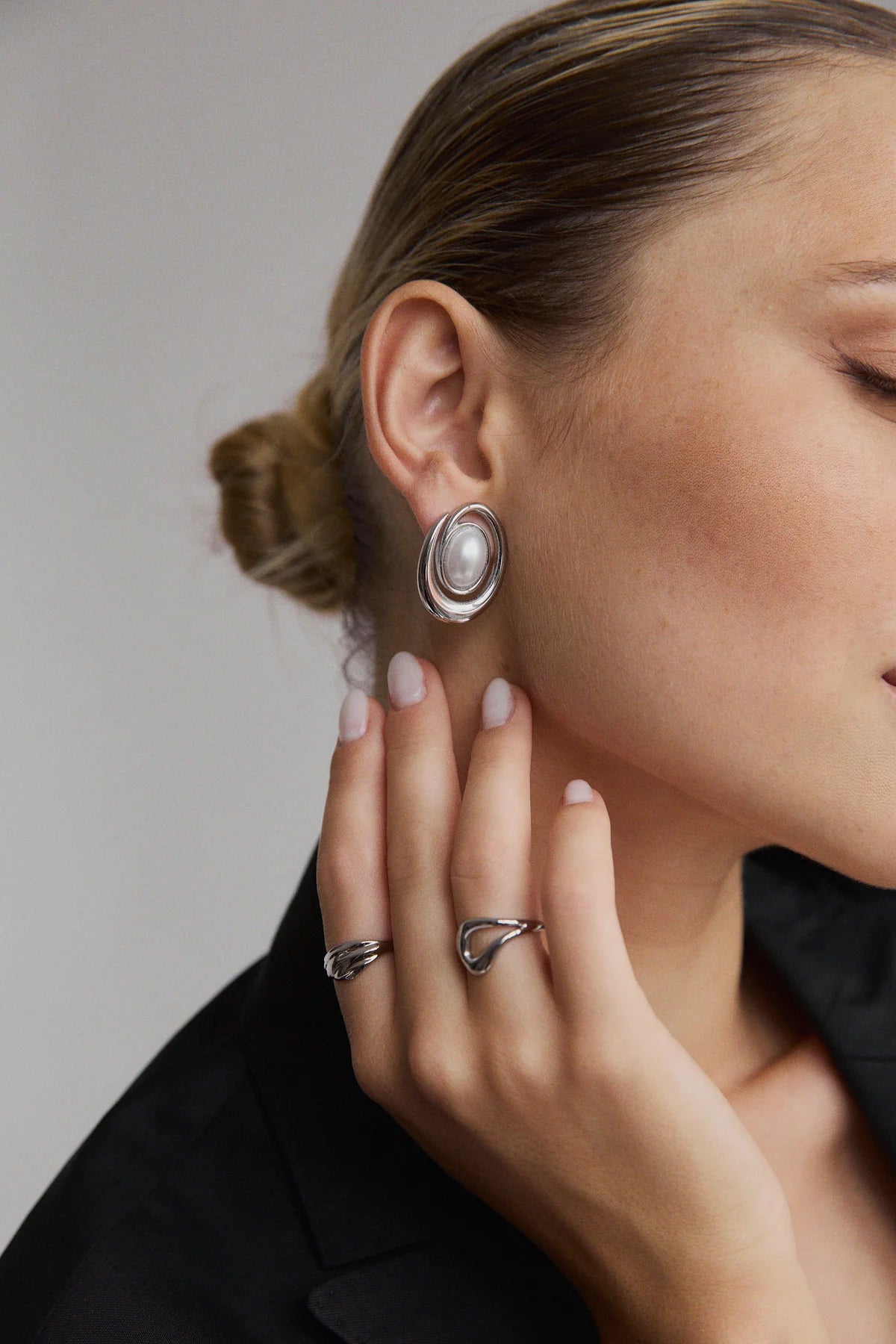 Gros plan sur la bague Gia portée, en duo avec une boucle d’oreille perle – finition brillante