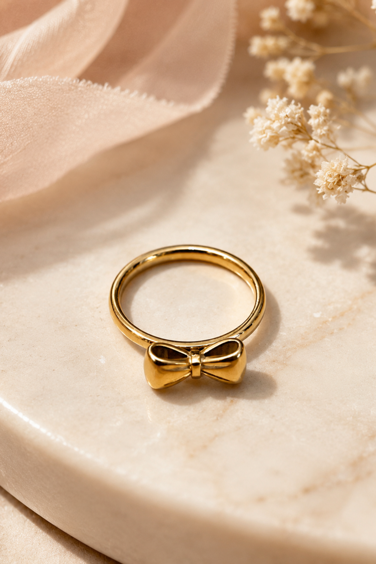 Gros plan de la bague Ruban Nœud Or posée sur une surface beige, montrant son design en forme de nœud doré.