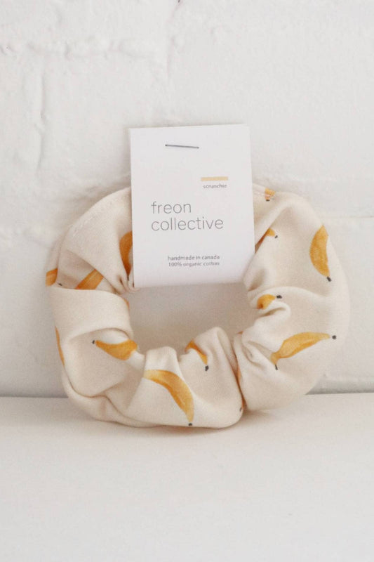 Chouchou coton bio motif bananes présenté contre un mur blanc – étiquette visible