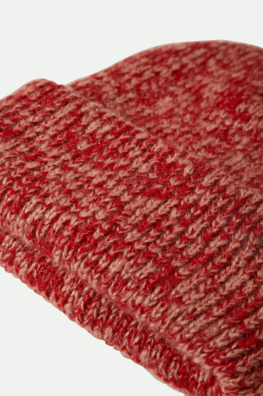 Gros plan sur la texture tricotée du bonnet rouge chiné en maille épaisse et douce.