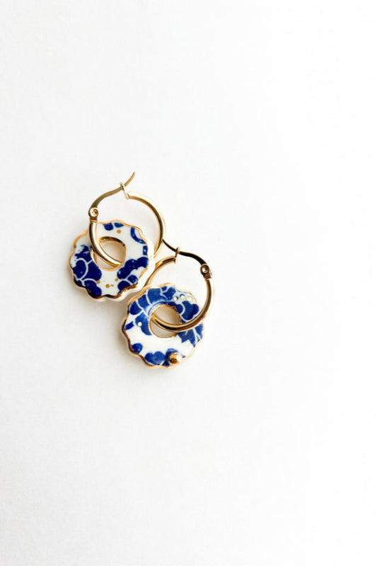 Boucles d’oreilles Donna bleu posées sur fond blanc, design rond ajouré en céramique