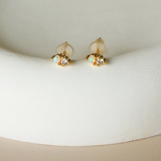 Boucles Elaro sur support blanc – détail des pierres scintillantes et monture dorée