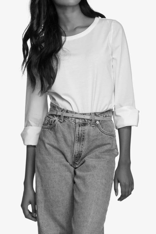 Ceinture noire fine portée à la taille sur un jeans taille haute avec haut blanc