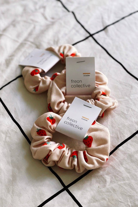 Chouchou en coton biologique motif fraises posé sur un lit – motif fruité et tissu doux