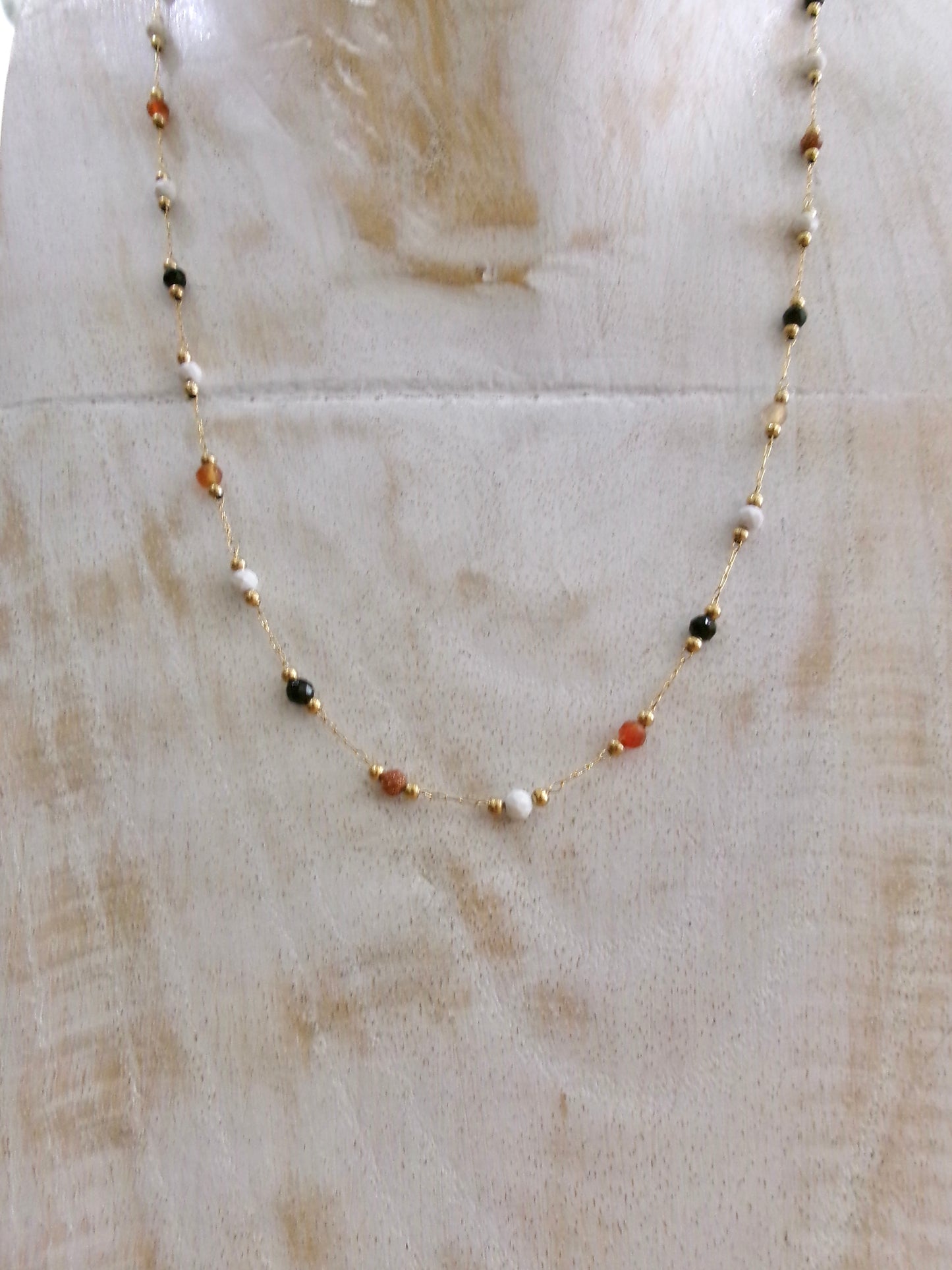 collier fin en acier doré avec perles naturelles onyx, agate et pierre du soleil sur fond neutre