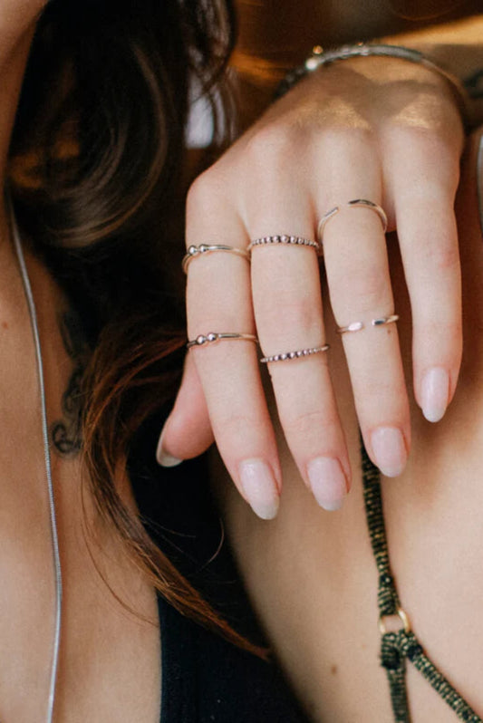 Bague Dots Argent portée avec d’autres bagues fines, détail perlé minimaliste en argent sterling 925.