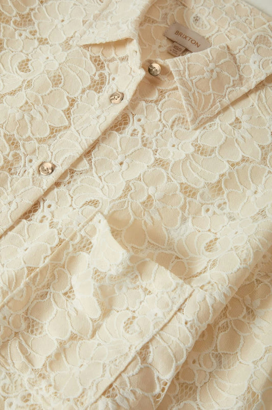 Zoom sur le col boutonné de la chemise crème – dentelle florale délicate