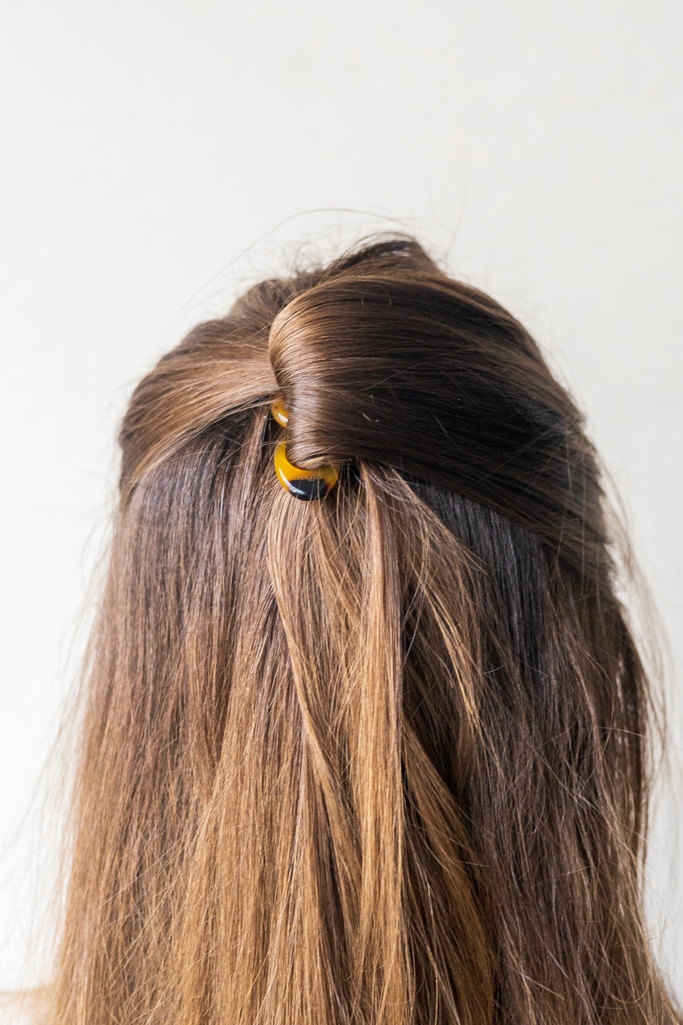 Vue arrière d’une coiffure demi-chignon avec une épingle effet écaille – format mini