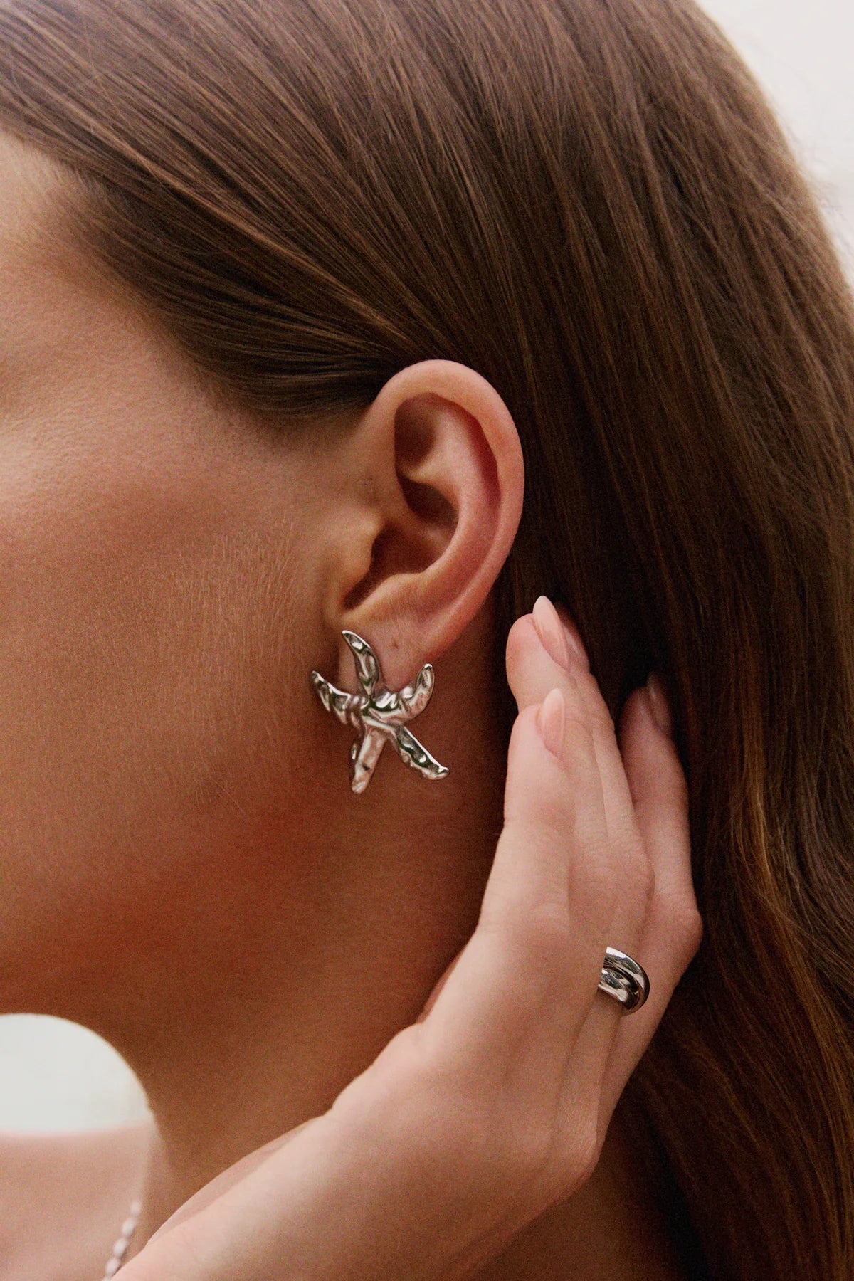 Gros plan sur boucle d’oreille étoile de mer finition argent martelé – détail du bijou original