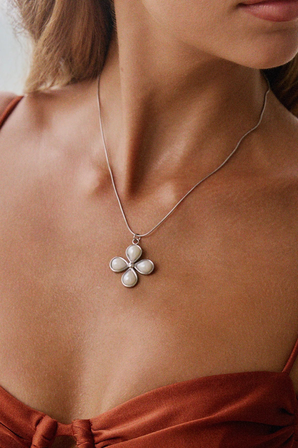 Zoom sur pendentif fleur argent avec quatre perles nacrées – bijou délicat sur peau nue
