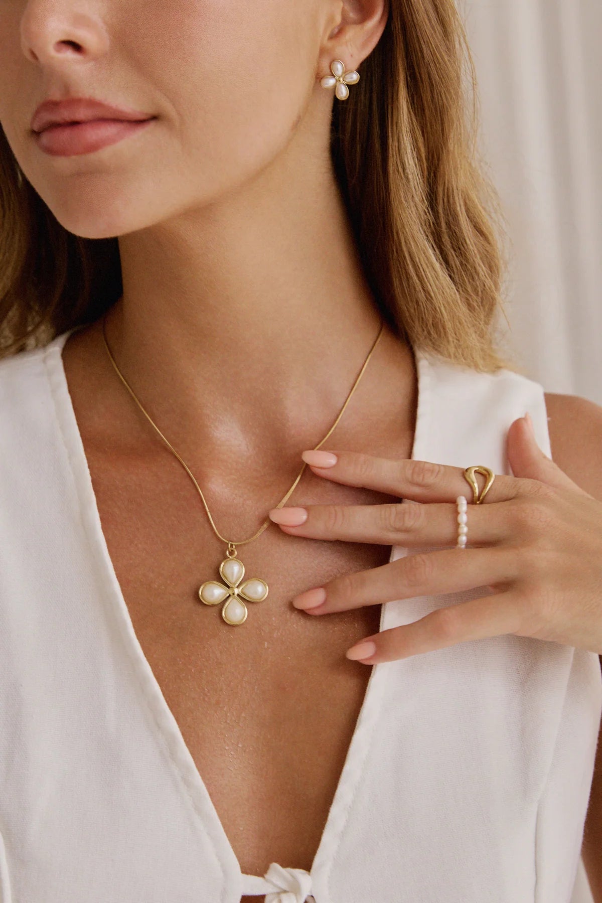 Zoom sur pendentif fleur dorée à perles nacrées – bijou délicat et lumineux, accompagné de bagues