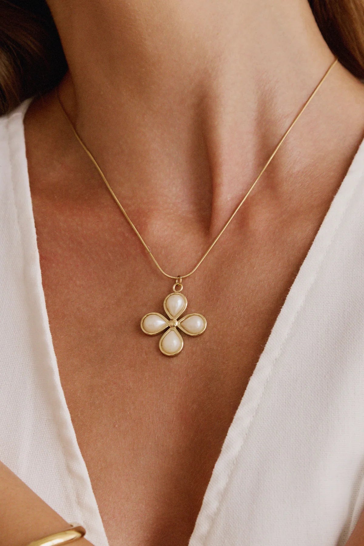 Gros plan sur le collier doré à pendentif fleur perlé – bijou féminin au style intemporel