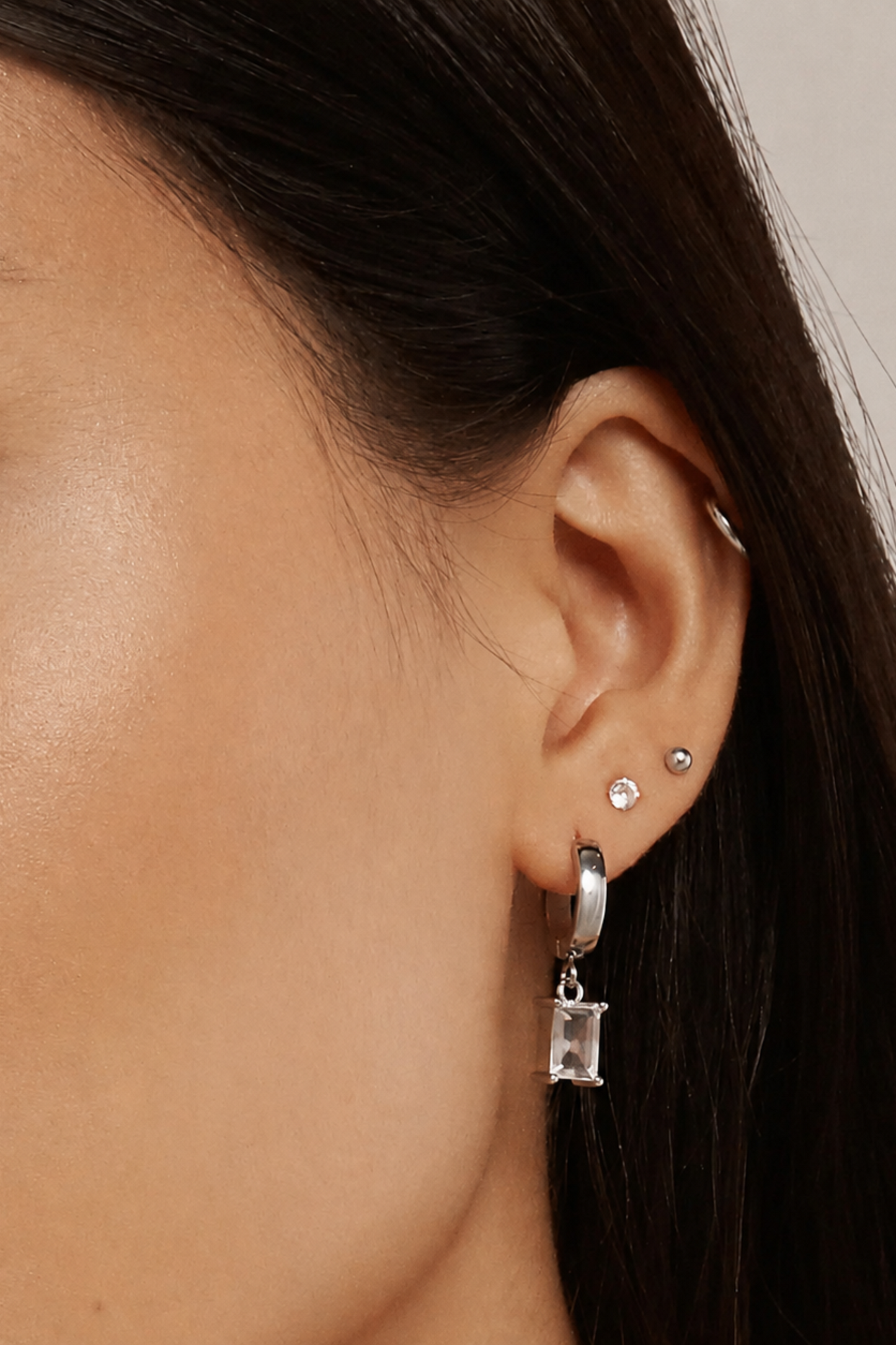 Gros plan des boucles d’oreilles Icy Argent portées, avec anneau argenté et zircon cubique rectangulaire.