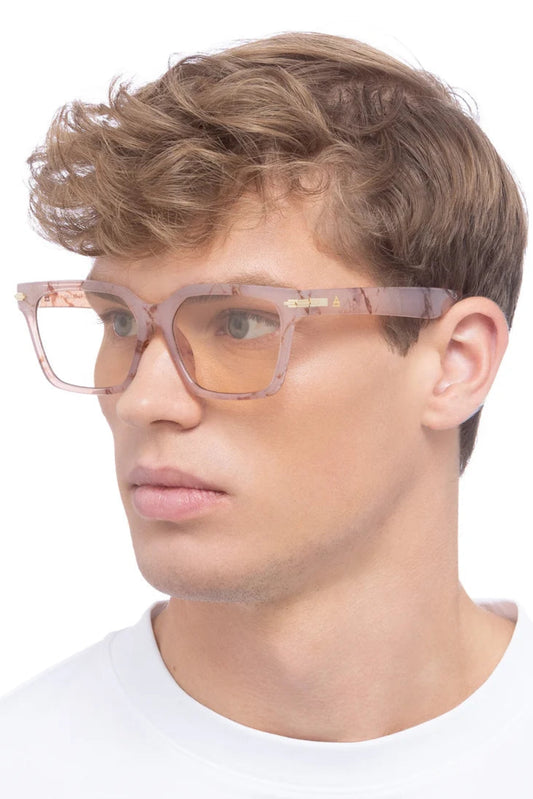 Lunettes de soleil Maya Marbre Brumeux portées par un homme, avec monture carrée rose marbrée et verres teinte orge.