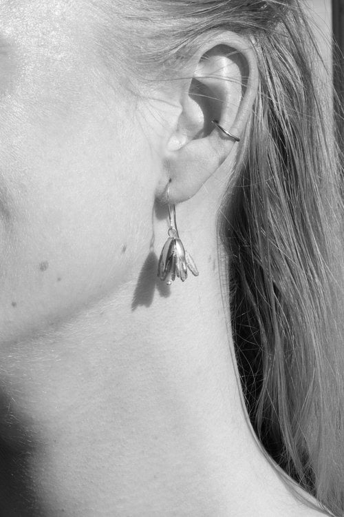 Vue rapprochée d’une boucle d’oreille Malli portée – forme fleur légère et délicate