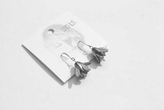 Boucles d’oreilles Malli en textile posées sur une carte – forme florale et finition satinée