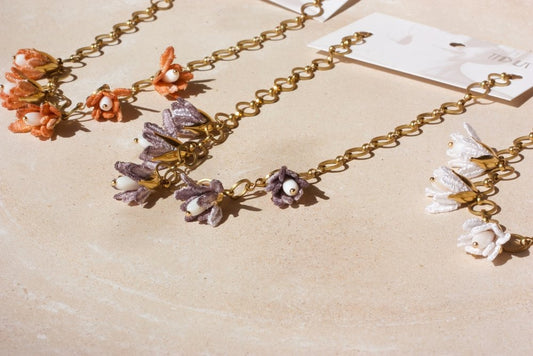 Zoom sur les fleurs du collier Malli lavande – perles blanches et pétales en textile satiné