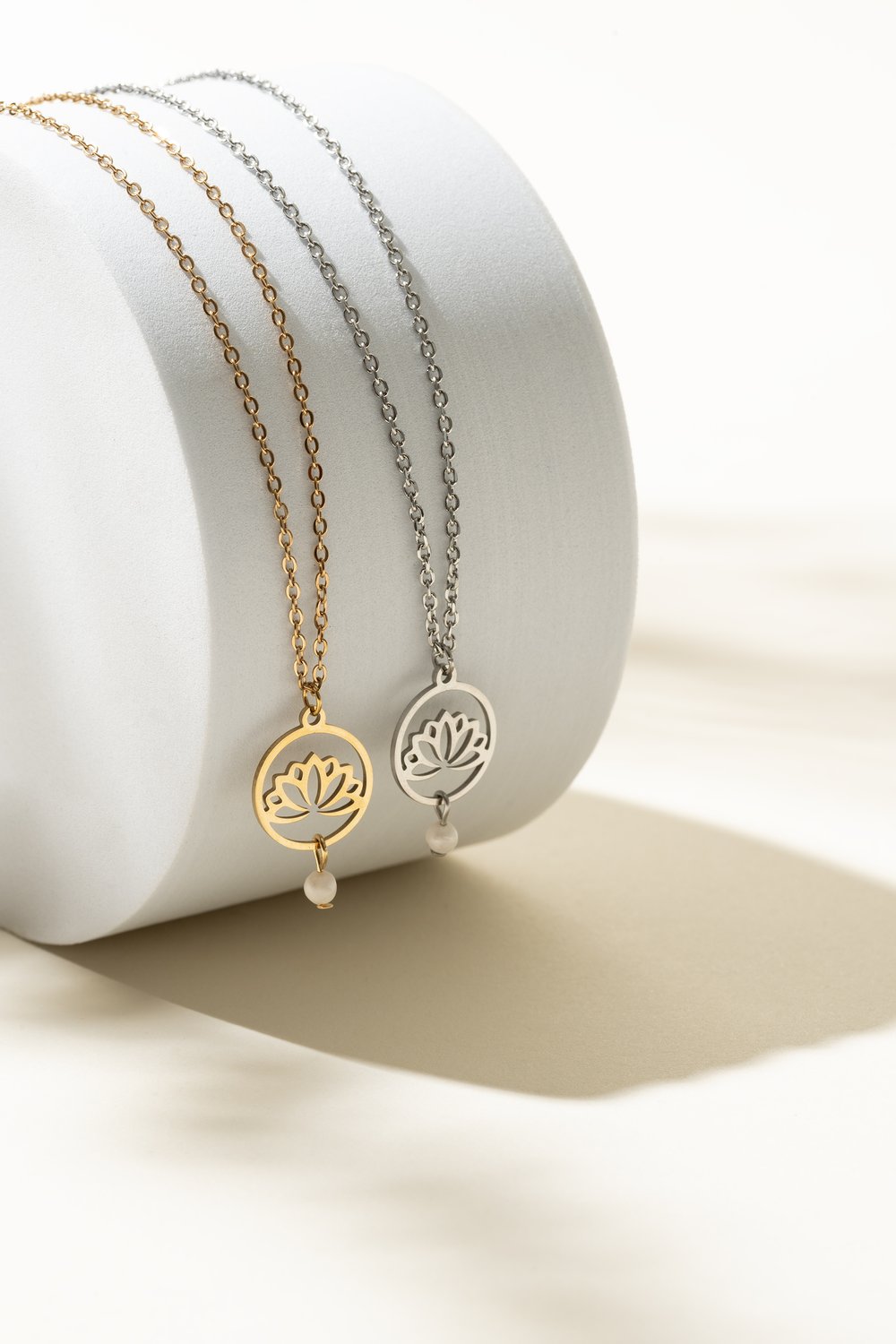 Collier en acier inoxydable avec pendentif lotus et perle d’eau douce sur fond crème