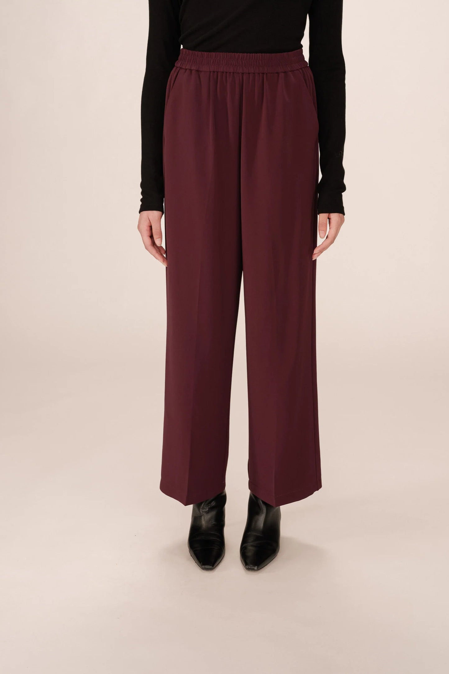 Vue avant du pantalon Noblesse bordeaux coupe droite et taille élastique porté avec un haut noir et des bottines noires.