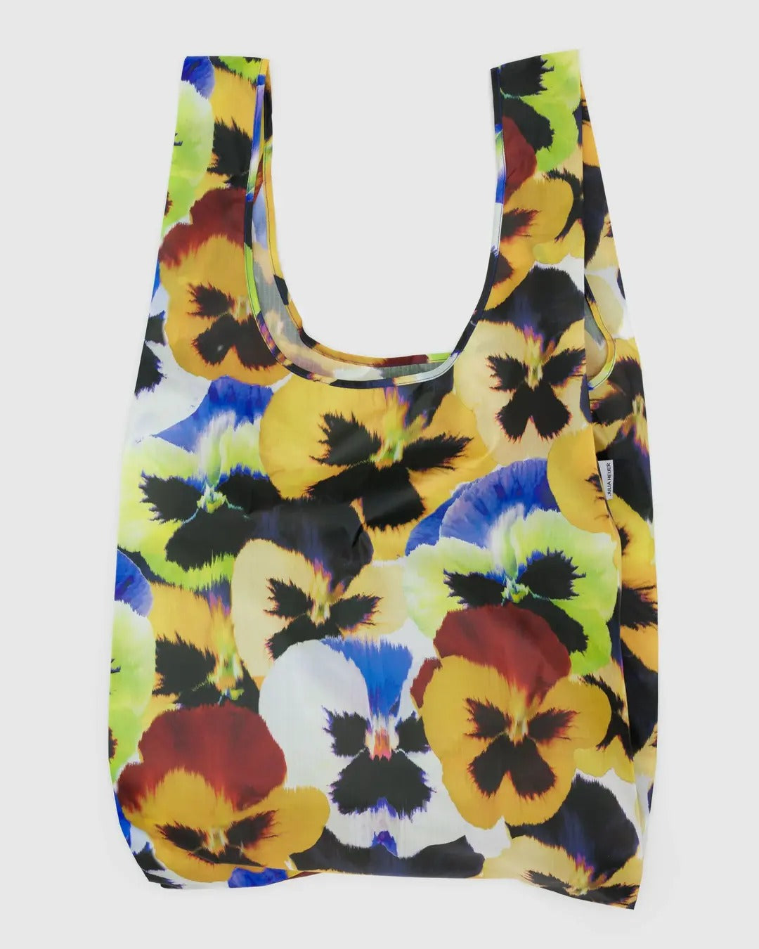 Sac réutilisable de la marque Baggu avec un imprimé floral éclatant représentant des pensées aux couleurs vives : jaune, bleu, rouge et vert sur fond noir. Ce sac léger et résistant est conçu pour transporter facilement vos courses ou vos effets personnels. Il dispose de deux anses larges et d’une ouverture spacieuse pour un accès pratique. Fabriqué en matière durable et facilement pliable, il se range aisément dans un sac à main ou une poche. Un accessoire polyvalent et esthétique pour un usage quotidien.