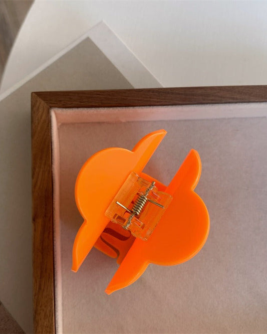 Pince à cheveux fleur en acétate orange avec centre jaune et feuille verte, vue en angle
