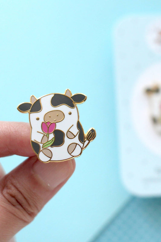 Pin’s vache mignon avec tulipe rose tenu dans la main avec finition dorée