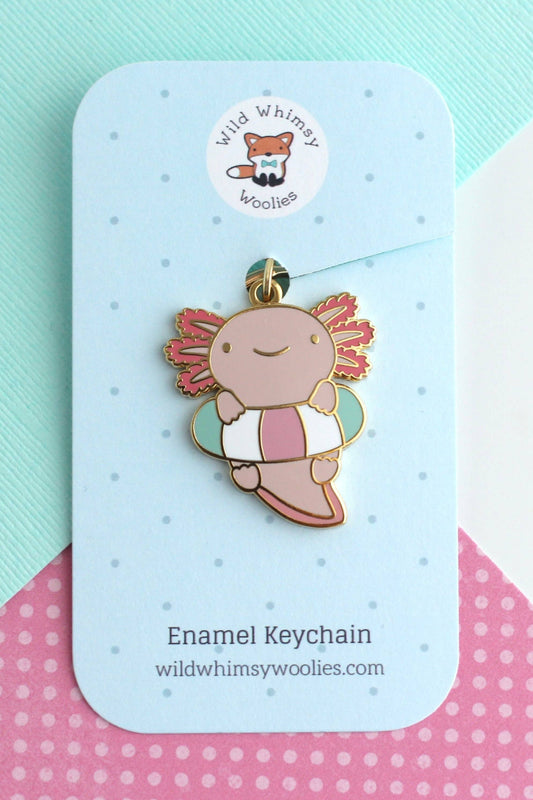 Porte-clés Axolotl Flottant en émail dur doré présenté sur carte bleue, couleurs rose et turquoise.