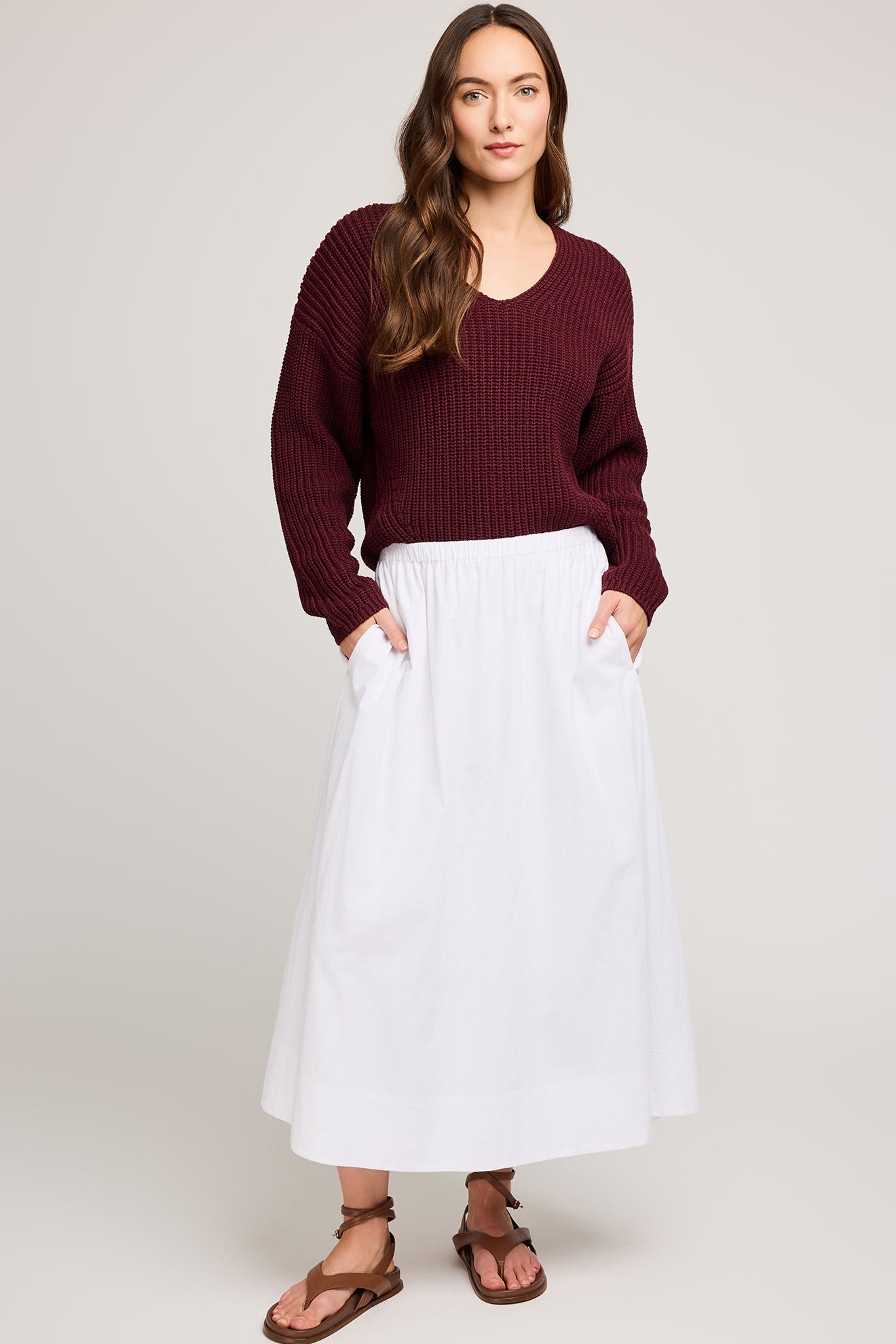 Photo du pull en maille merlot porté avec une jupe blanche pour un look automnal élégant