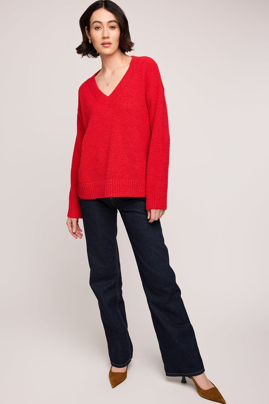 Vue complète du pull rouge coupe oversize avec encolure en V et finition côtelée porté avec un jean