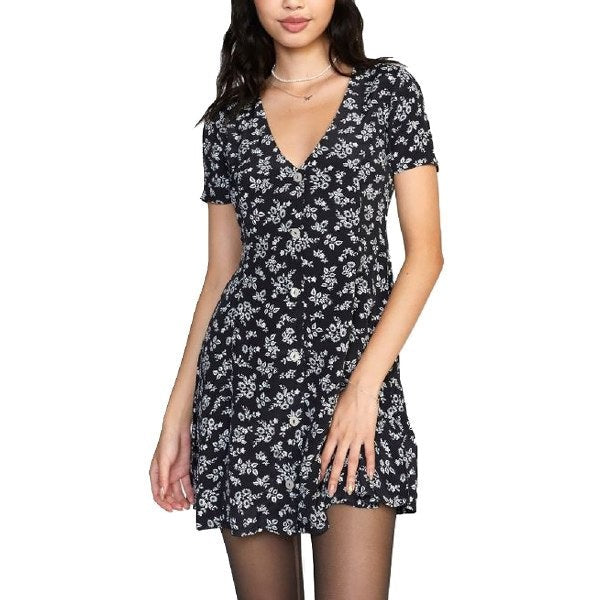 Robe courte noire à manches courtes avec un imprimé floral blanc délicat. Elle présente un décolleté en V et une coupe légèrement évasée qui flatte la silhouette. Les boutons sur le devant ajoutent une touche féminine et élégante. Idéale pour un look casual chic, à porter avec des collants ou jambes nues selon la saison.