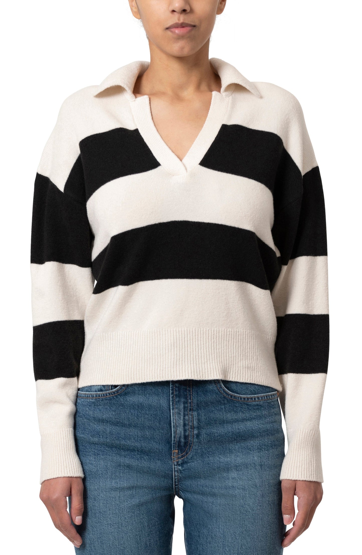 Pull ample à col V avec de larges rayures grises et vertes. Le modèle porte un jean bleu foncé.