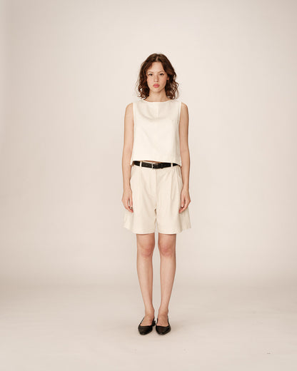 Un bermuda écru élégant et fluide, conçu dans un tissu léger. Il présente une taille ajustée avec passants pour ceinture, des plis discrets à l’avant et des poches latérales. Un modèle polyvalent, idéal pour un look raffiné et décontracté.