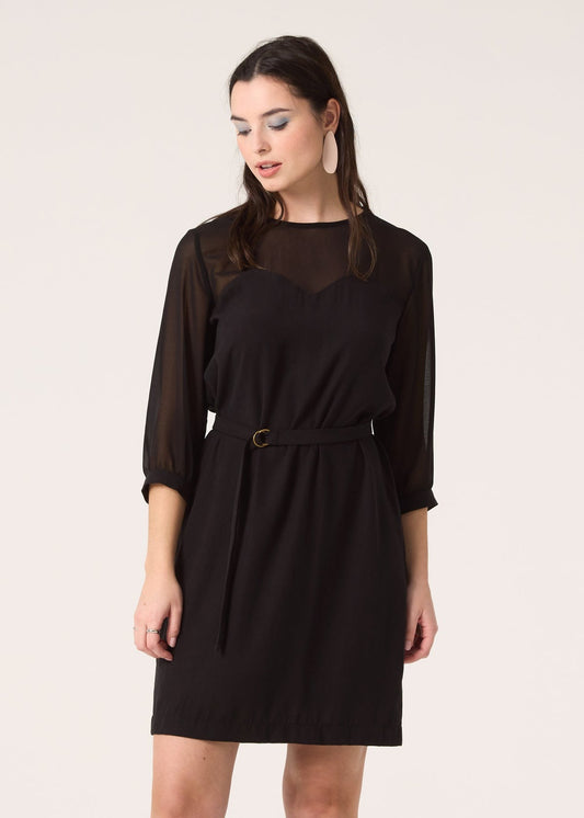 Robe aux genoux à manches 3/4 noir avec transparence aux épaules, coupe ample et découpe bustier à la poitrine avec ceinture à la taille. Vu de face zoom