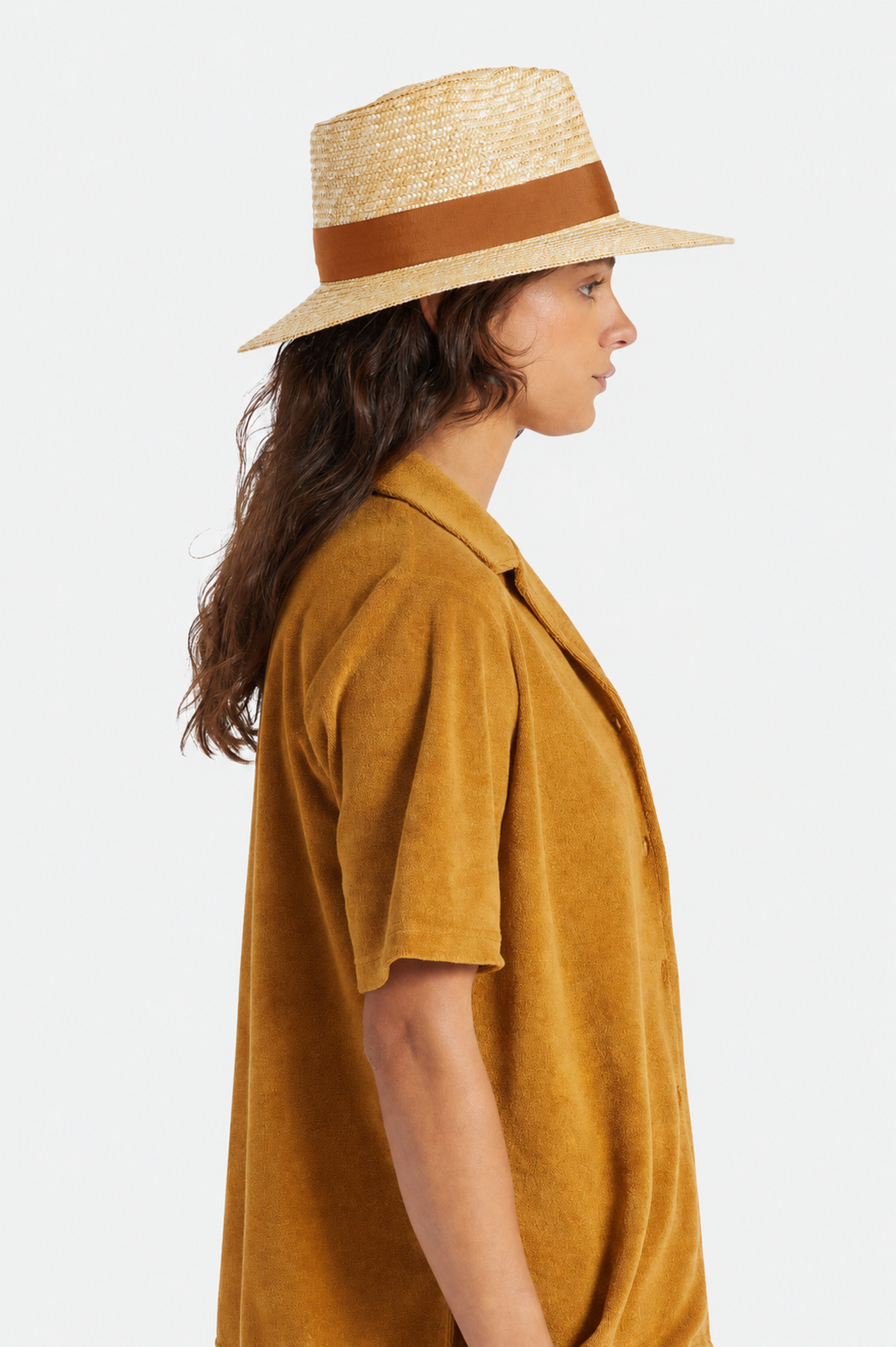Femme portant le chapeau Barbara brun de profil, avec bord large, bande brune contrastante et style estival chic.