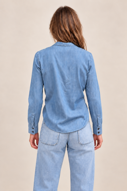 Chemise en denim bleu clair vue de dos, avec manches longues, poignets boutonnés et tombé légèrement arrondi.