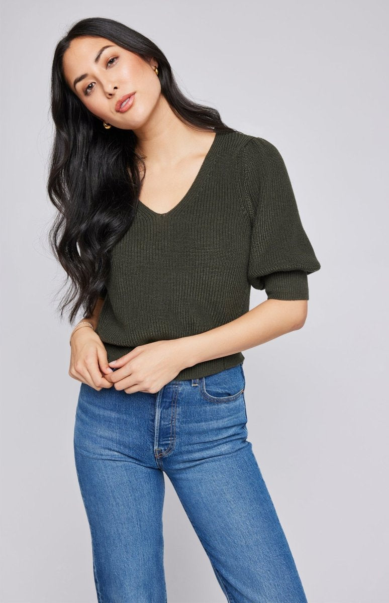 Pull col V à manches bouffantes en tricot trés doux de couleur vert olive. Manches 3/4, resserré aux coude et la taille porté avec un jeans bleu.. Vu de devant