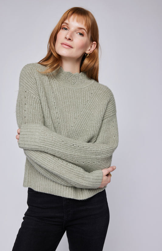 Pull en maille vert sauge avec col montant côtelé, coupe ample et manches longues pour un look tendance. Confortable, chaud et stylé, ce pull oversize s'associe facilement avec un jean ou une jupe. Idéal pour un style automnal chic et décontracté.