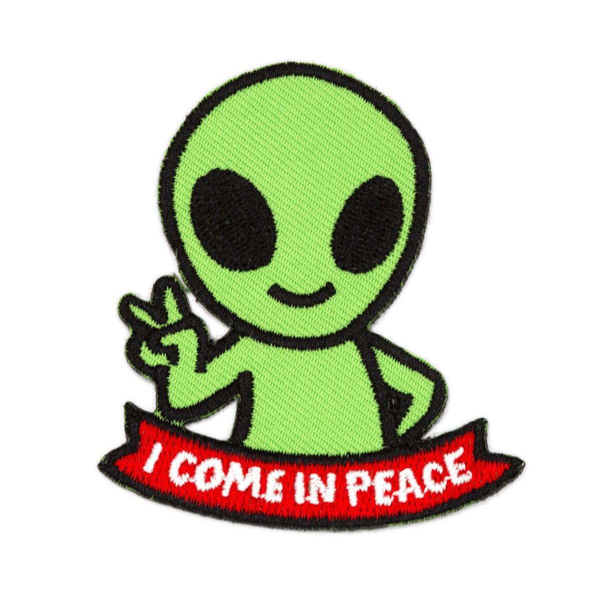 Patch en forme d’alien vert avec une banderole sur laquelle il est écrit en anglais I come in peace. L’arrière-plan est un fond blanc. 