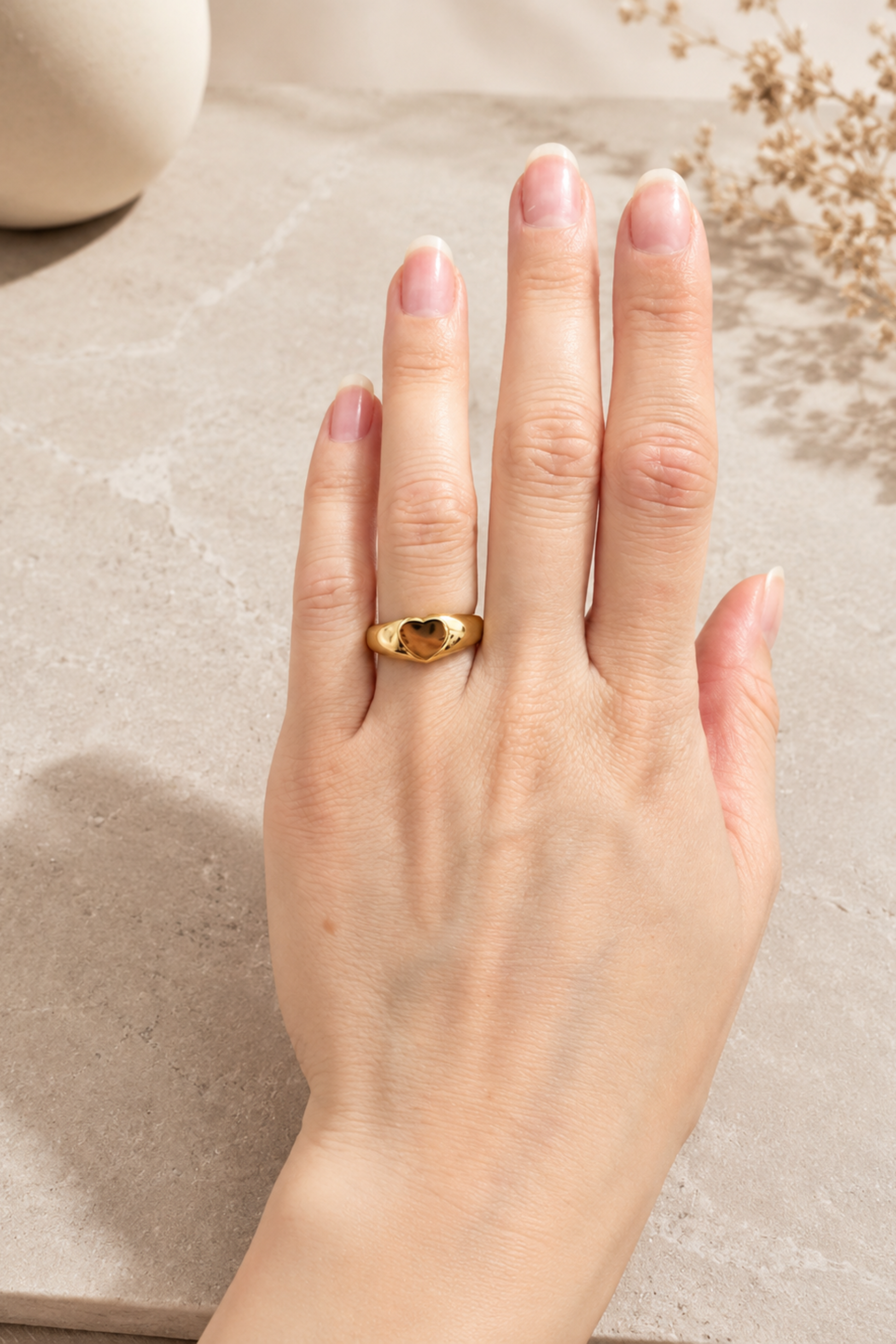 Bague cœur dorée portée sur la main, design bombé brillant et style romantique.
