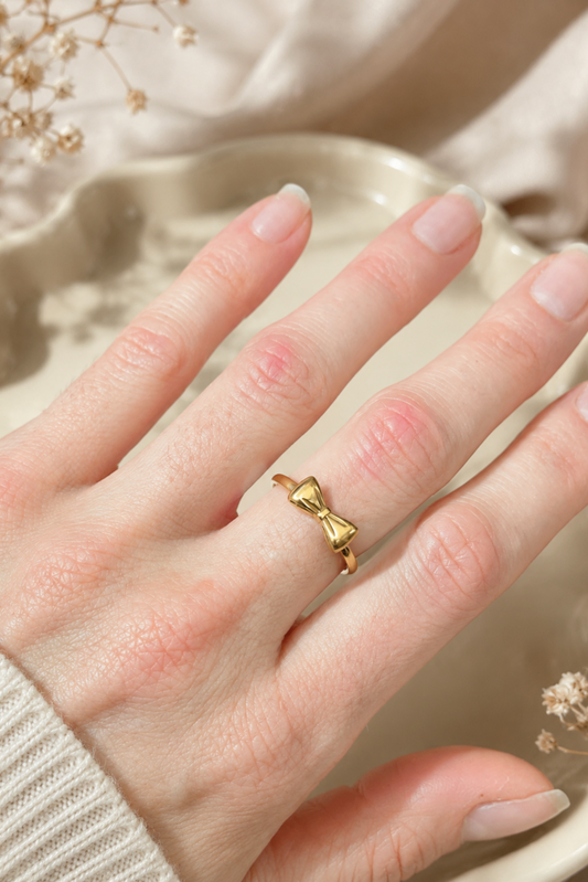 Bague Ruban Nœud Or portée à la main, avec petit nœud doré délicat en acier inoxydable plaqué or.