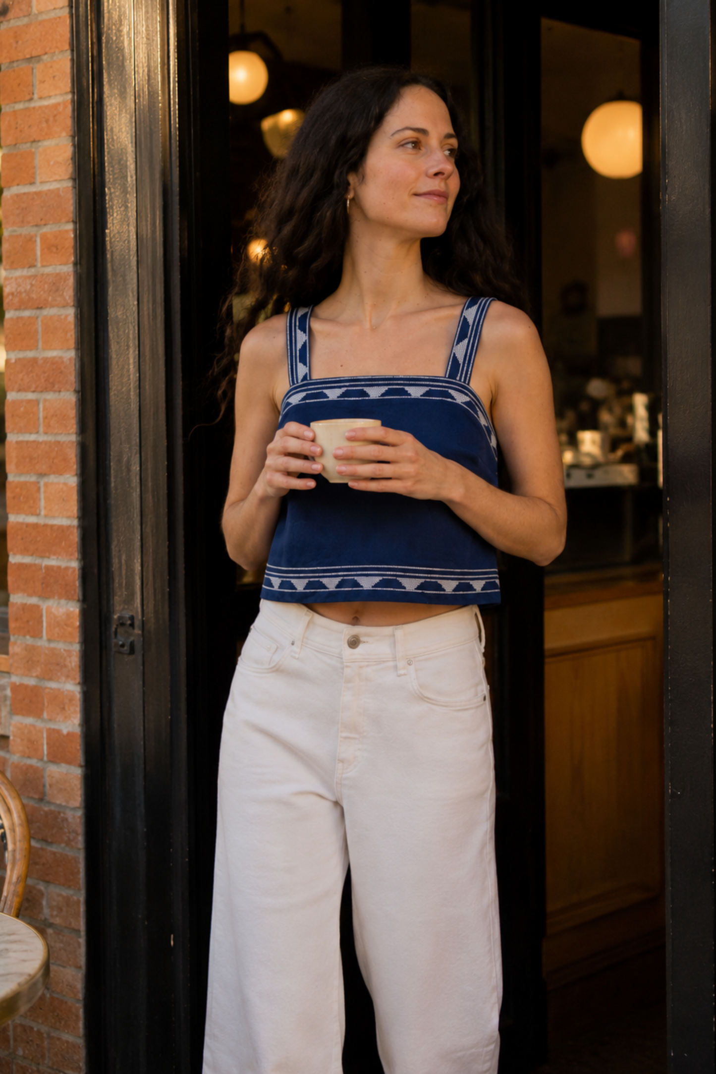 Femme portant le débardeur bustier Bali bleu devant un café, avec motifs ethniques contrastés et coupe courte estivale.