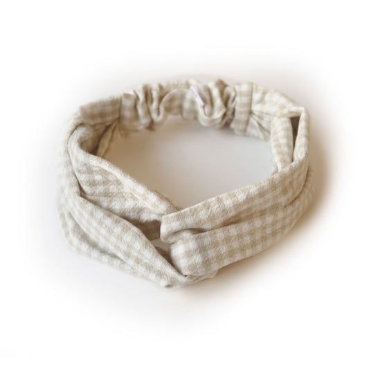 Bandeau croisé sur le haut de la tête en tissu à motif à carreaux beige et blanc. 