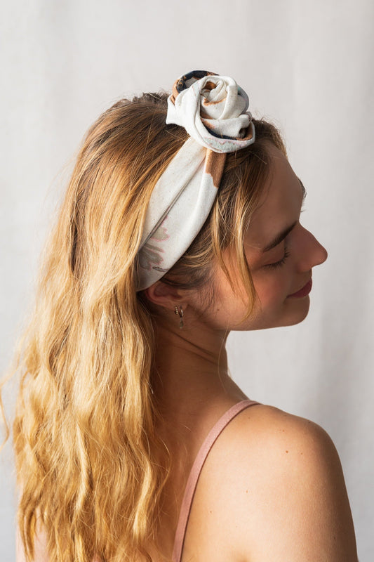 Femme vue de profil portant le bandeau floral noué façon fleur – style bohème

