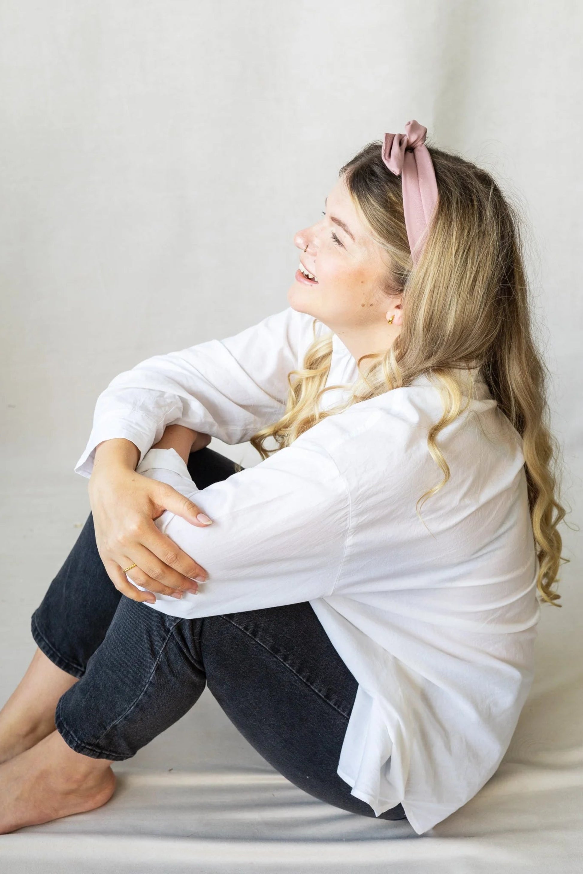 Détail du bandeau torsadé rose, noué sur le dessus de la tête porté avec chemise blanche